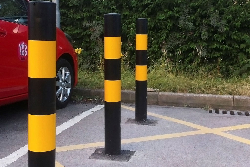 Cast-in black and yellow bollard installed in factory car park