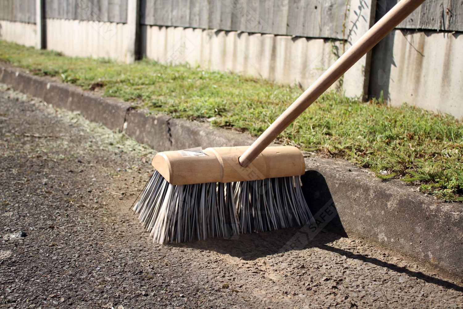 Yard, garden broom being used to sweep up grass cuttings