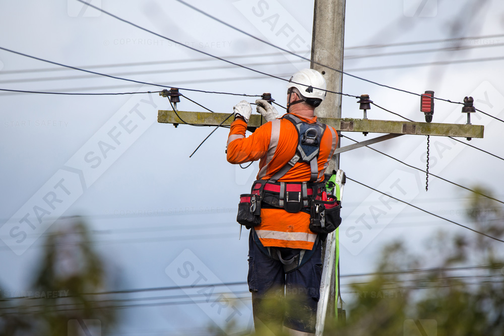 Linesman Wearing An Electrically Insulated Climbing Hard Hat While Working On Powerlines