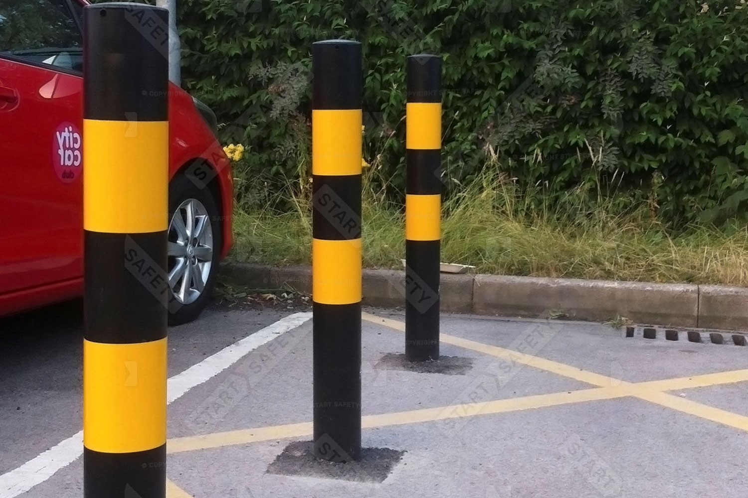 Cast-in black and yellow bollard installed in factory car park