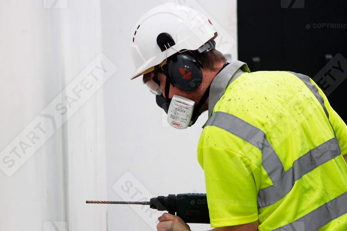 Construction Worker Drilling While Wearing A Hard Hat With Ear Defenders