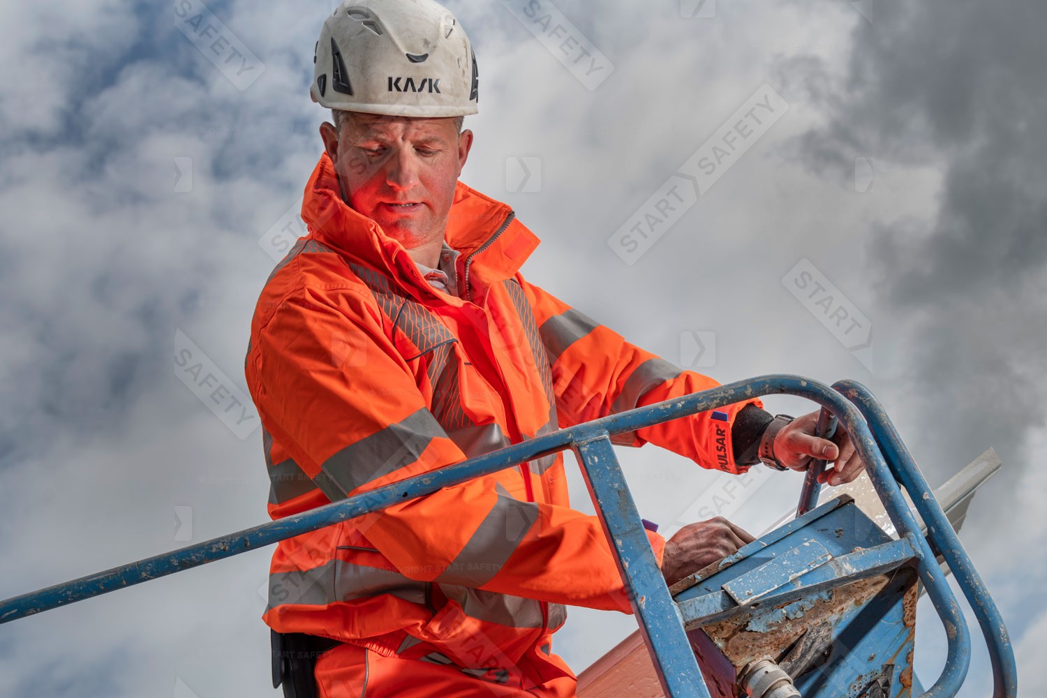 Construction Worker Wearing Orange Hi Vis Jacket In A Cherry Picker