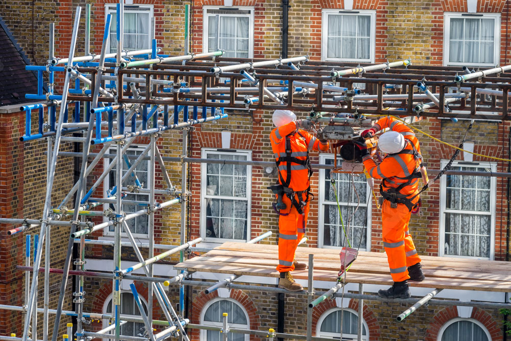 Scaffolders Working At Height With Hard Hats And Fall Restraints